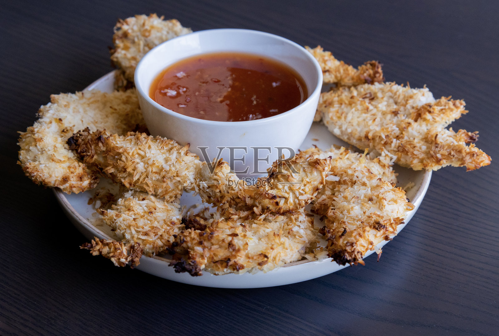 椰丝裹鸡胸肉，放在盘子里配有甜辣酱。热带风味菜肴，酥脆的口感，丰富的味道。照片摄影图片