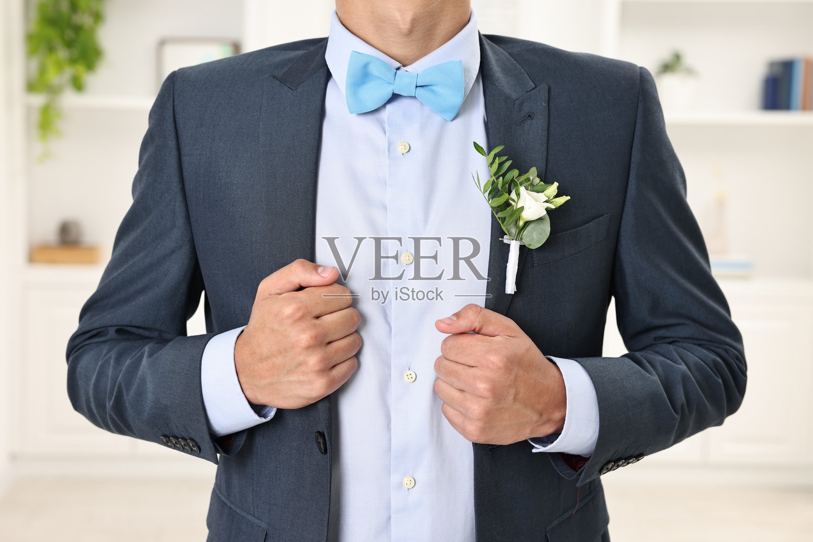 身穿西装的 groom 在室内，搭配时尚的胸花，特写镜头照片摄影图片