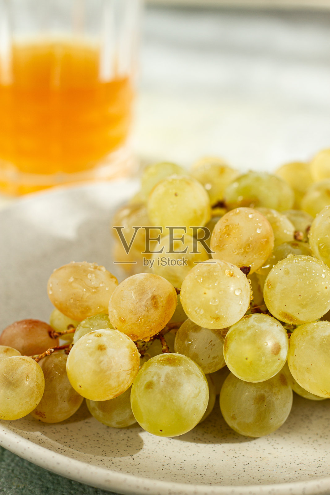 一串白葡萄，放在灰色盘子上，旁边有一杯白葡萄酒，俯视图，自然光，食品概念，无人。照片摄影图片