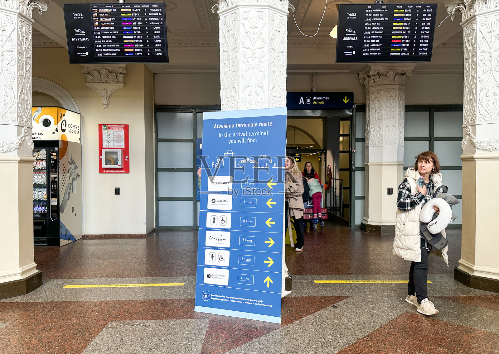 维尔纽斯机场大厅内的信息亭和航班显示板,旅客们在周围移动照片摄影图片