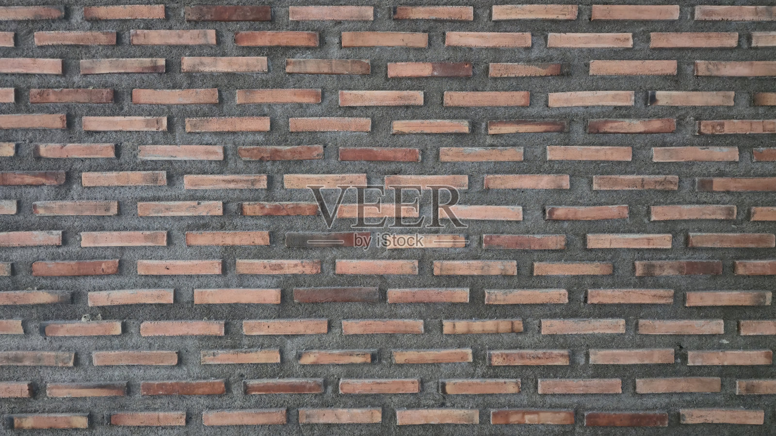 围栏由红色和橙色的砖块制成。旧砖围栏上有污渍和裂缝。照片摄影图片