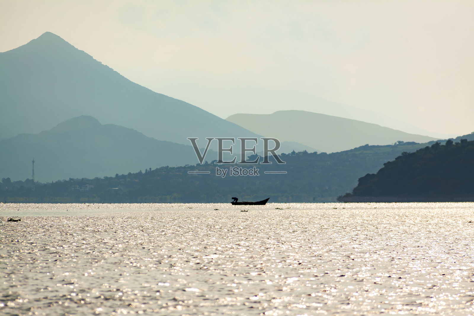 渔民在查帕拉湖的日落时分收集渔网。照片摄影图片