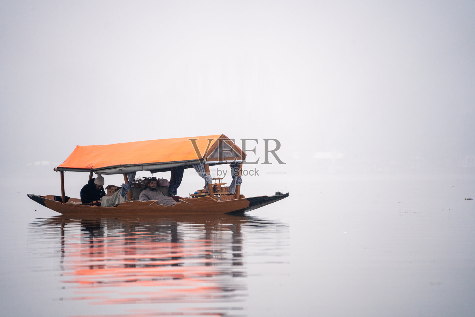游客坐在木制的香卡拉船上，船顶色彩斑斓，湖面被雾气笼罩，展现了受欢迎的旅游活动。照片摄影图片