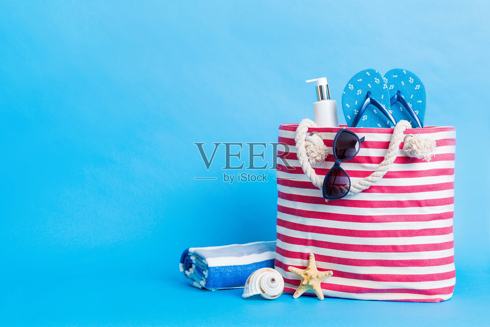 时尚的沙滩包与海滩配件。夏季假期概念。沙滩包的俯视图，配有防晒霜，留有文字空间。照片摄影图片