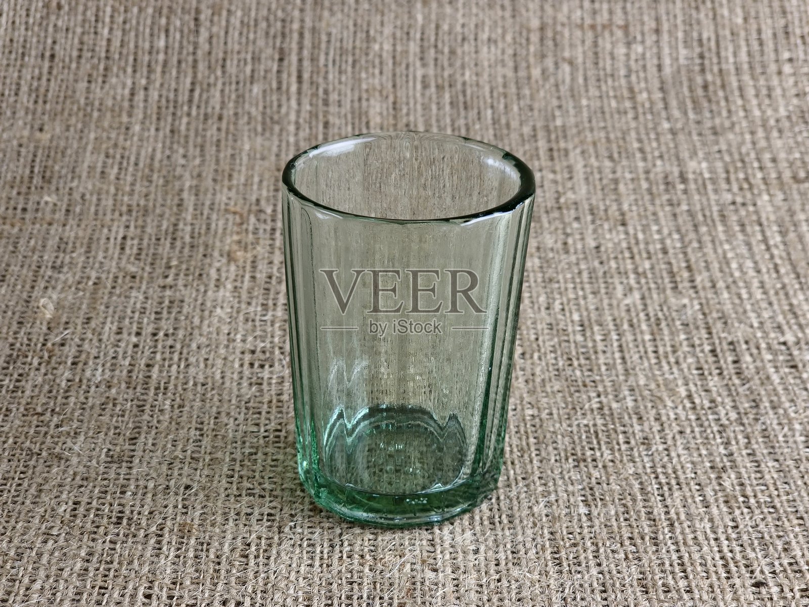 一只旧的多面体伏特加杯。在苏联，它被称为Granchik。一个空杯子放在麻布背景上。照片摄影图片