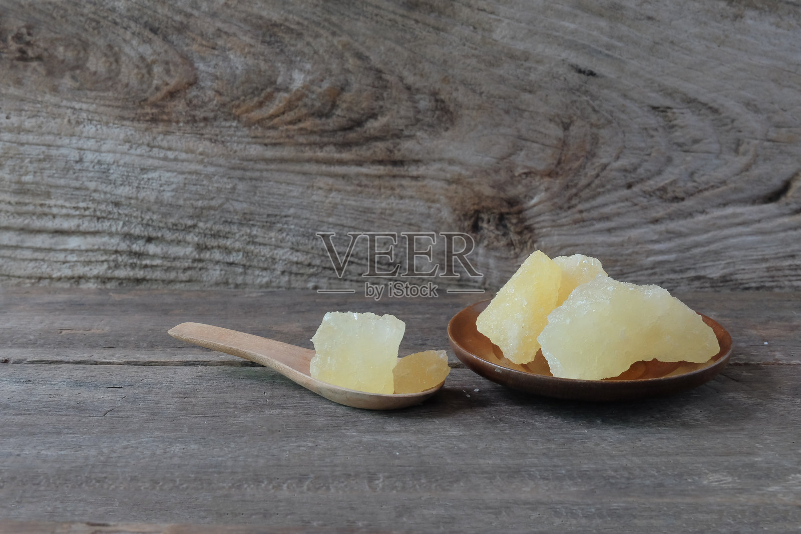 木勺上的冰糖，背景为古老的木材。甜食。照片摄影图片