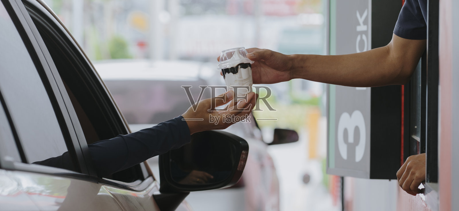 一位顾客在高峰时段从自取餐窗口的送餐员那里取食物。照片摄影图片