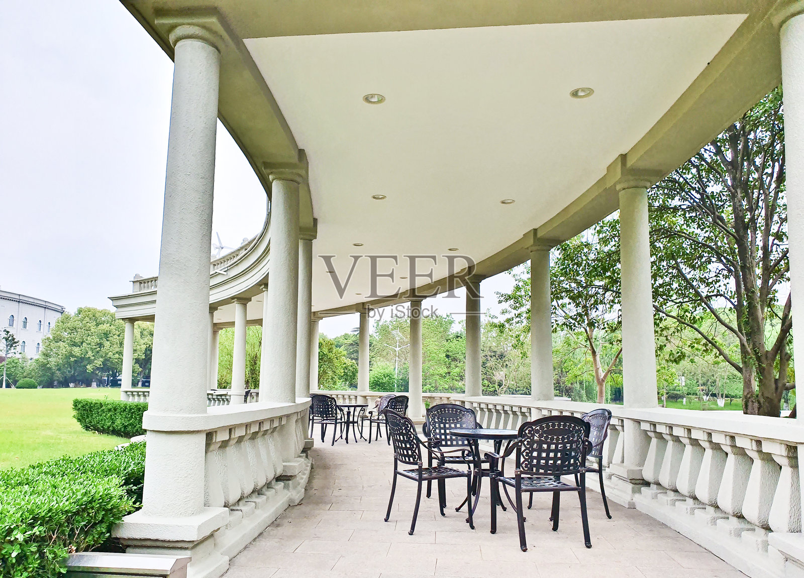 一个圆顶凉亭坐落在宁静的湖边，通过石头小道相连，四周环绕着郁郁葱葱的绿树和倒影。照片摄影图片