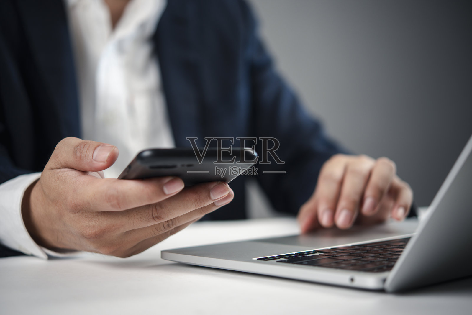 特写镜头：手握智能手机，正在使用笔记本电脑，商业科技，数字通信，在线协作，电子邮件或远程管理。照片摄影图片