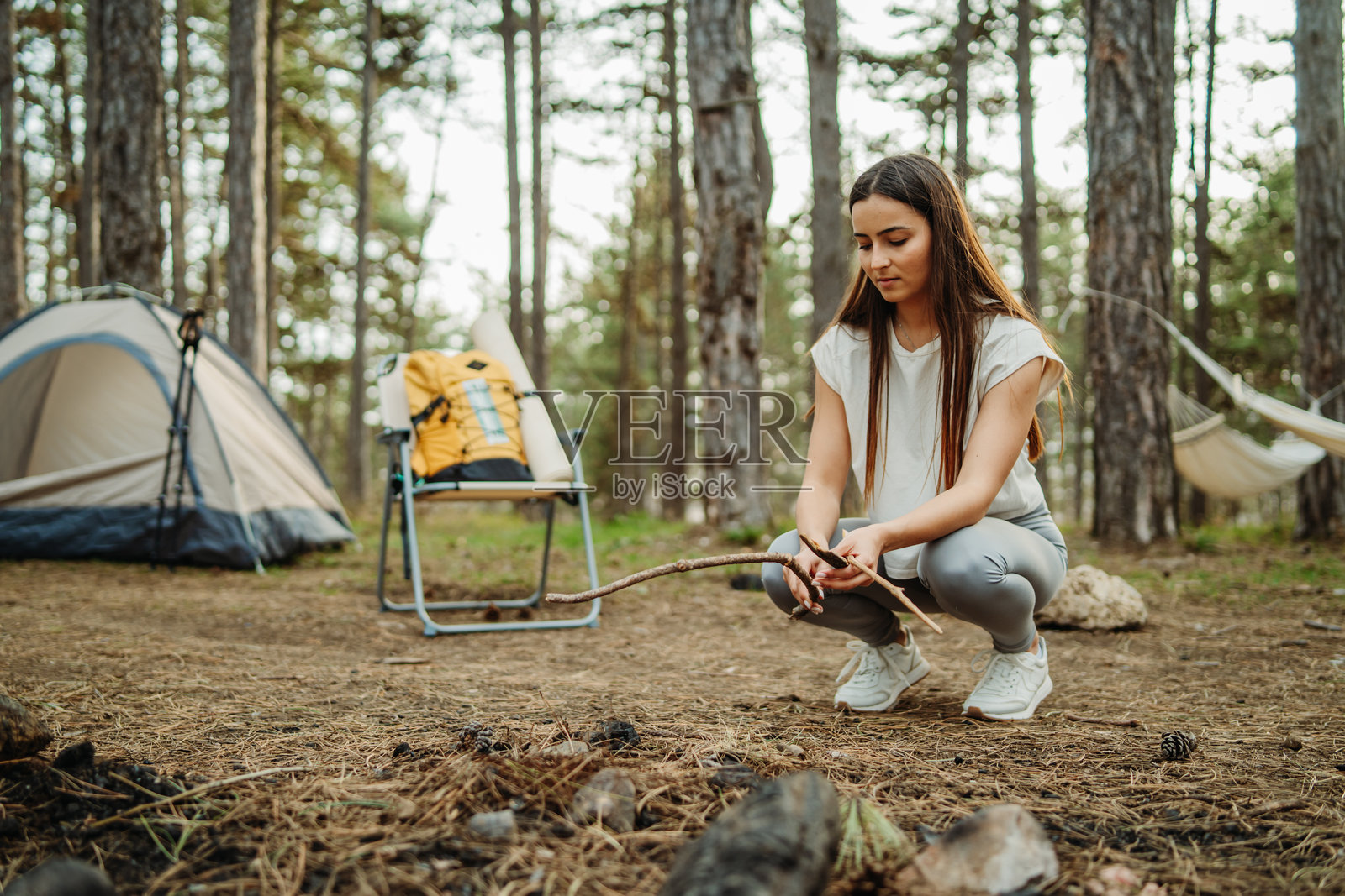 年轻的白人女性在风景如画的森林中为夜晚准备露营和篝火照片摄影图片