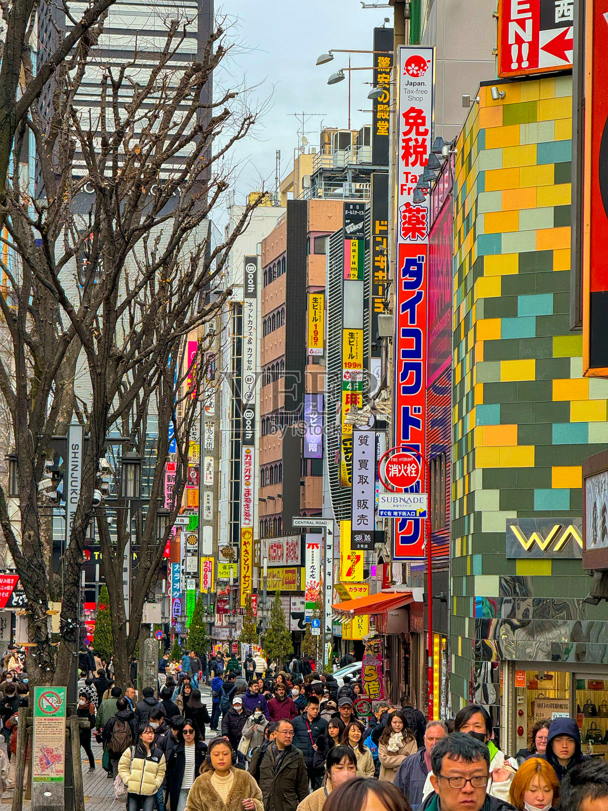 垂直：人群在东京新宿的五彩缤纷的购物街上行走。照片摄影图片
