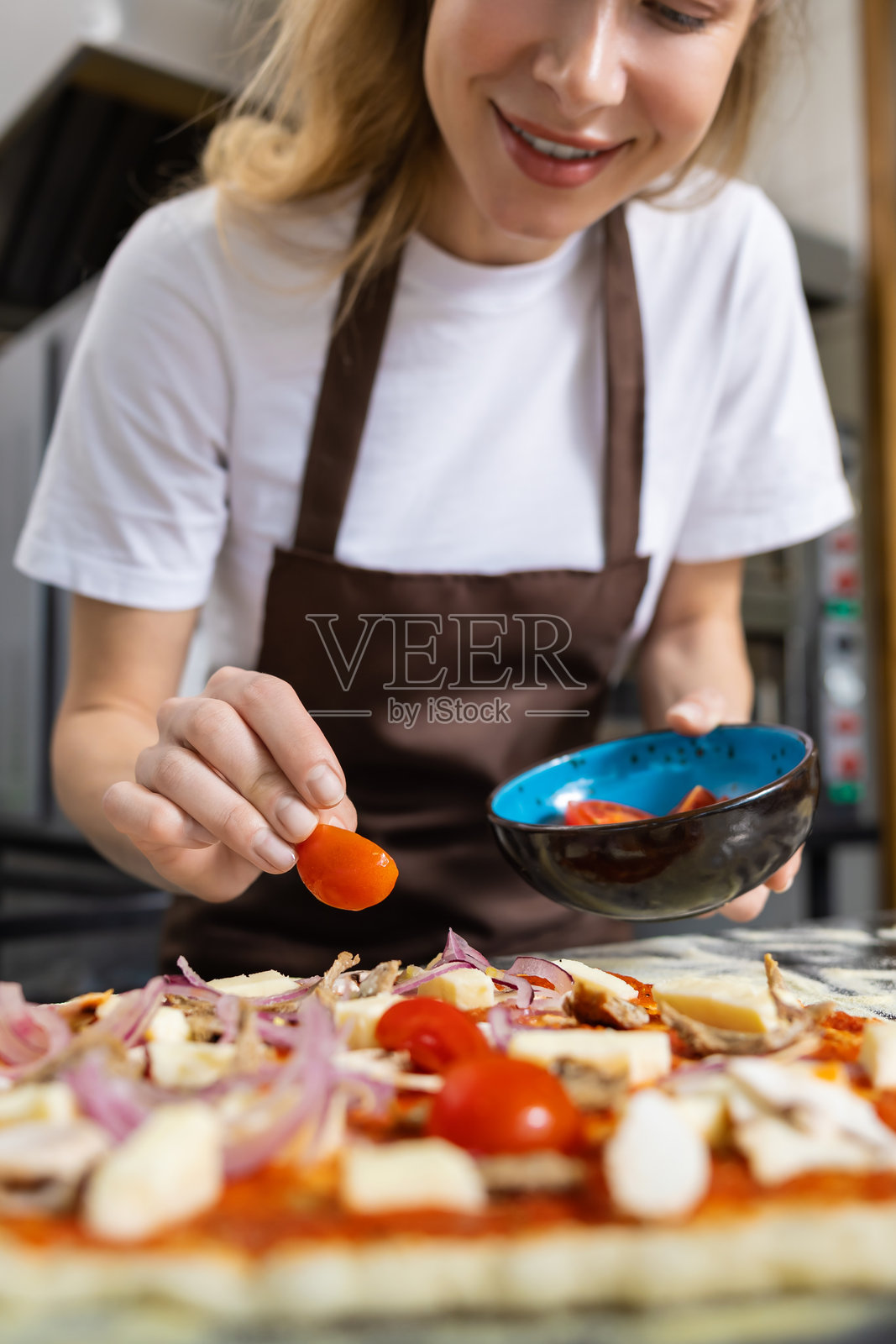 女人在比萨饼上撒番茄照片摄影图片