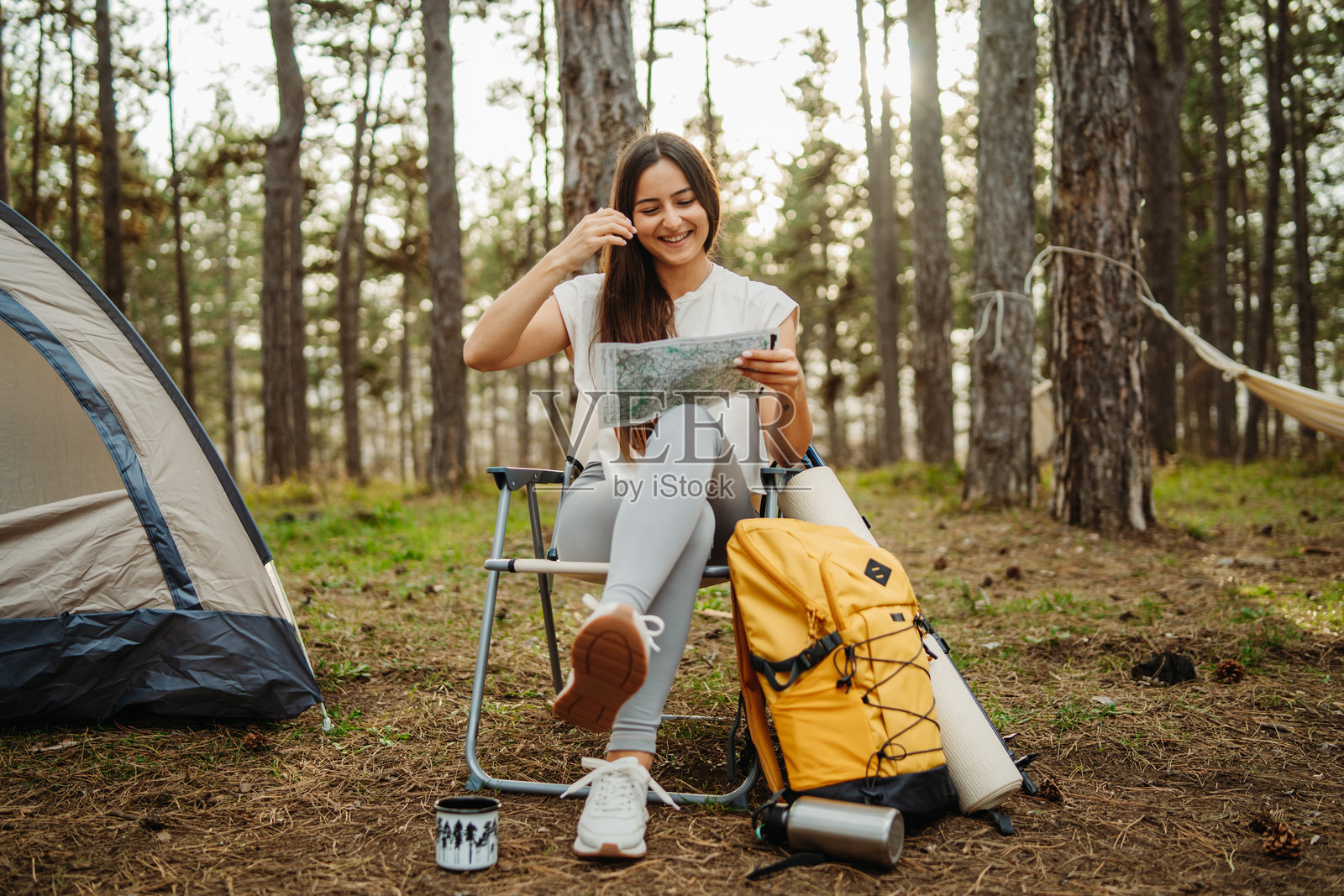年轻的白人女性在风景如画的森林中为夜晚准备营地和篝火照片摄影图片