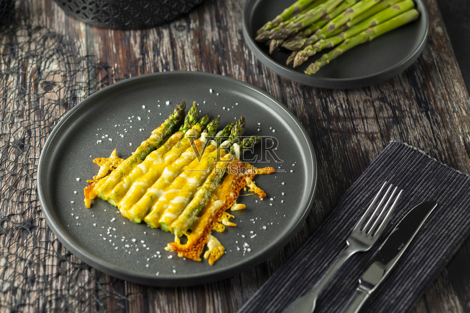 美味的烤芦笋上铺满融化的奶酪，放在灰色盘子上照片摄影图片