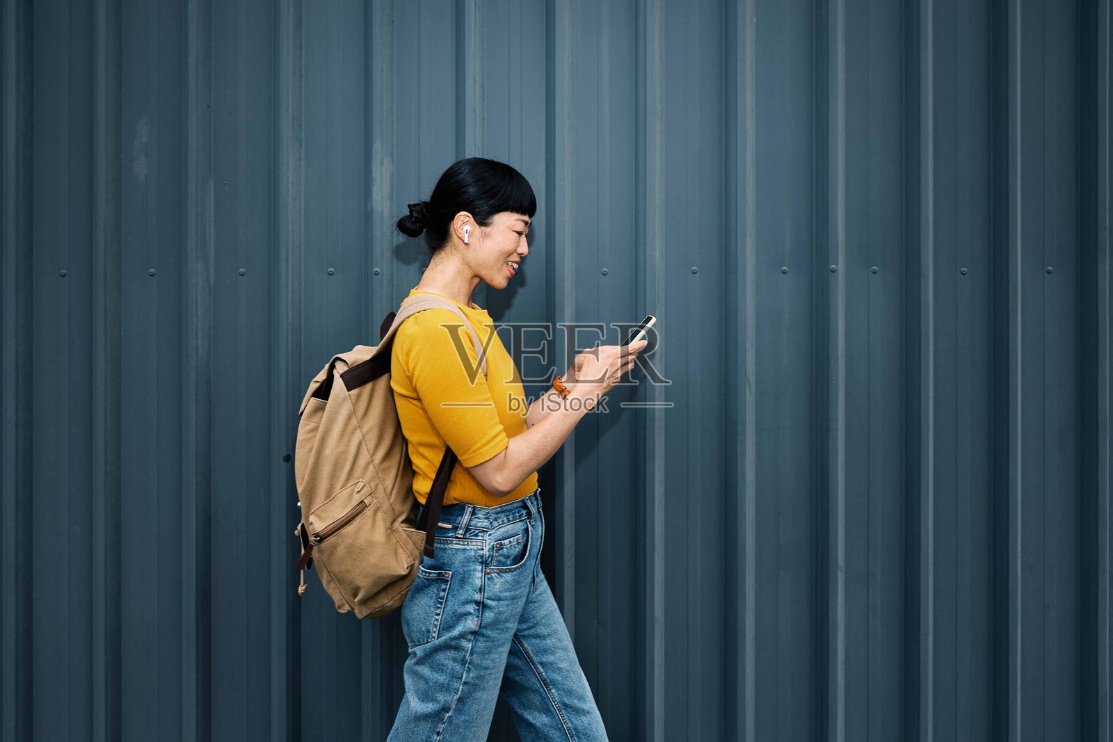 侧面视角的快乐时尚日本嬉皮士女性在街上用手机选择播放列表。照片摄影图片