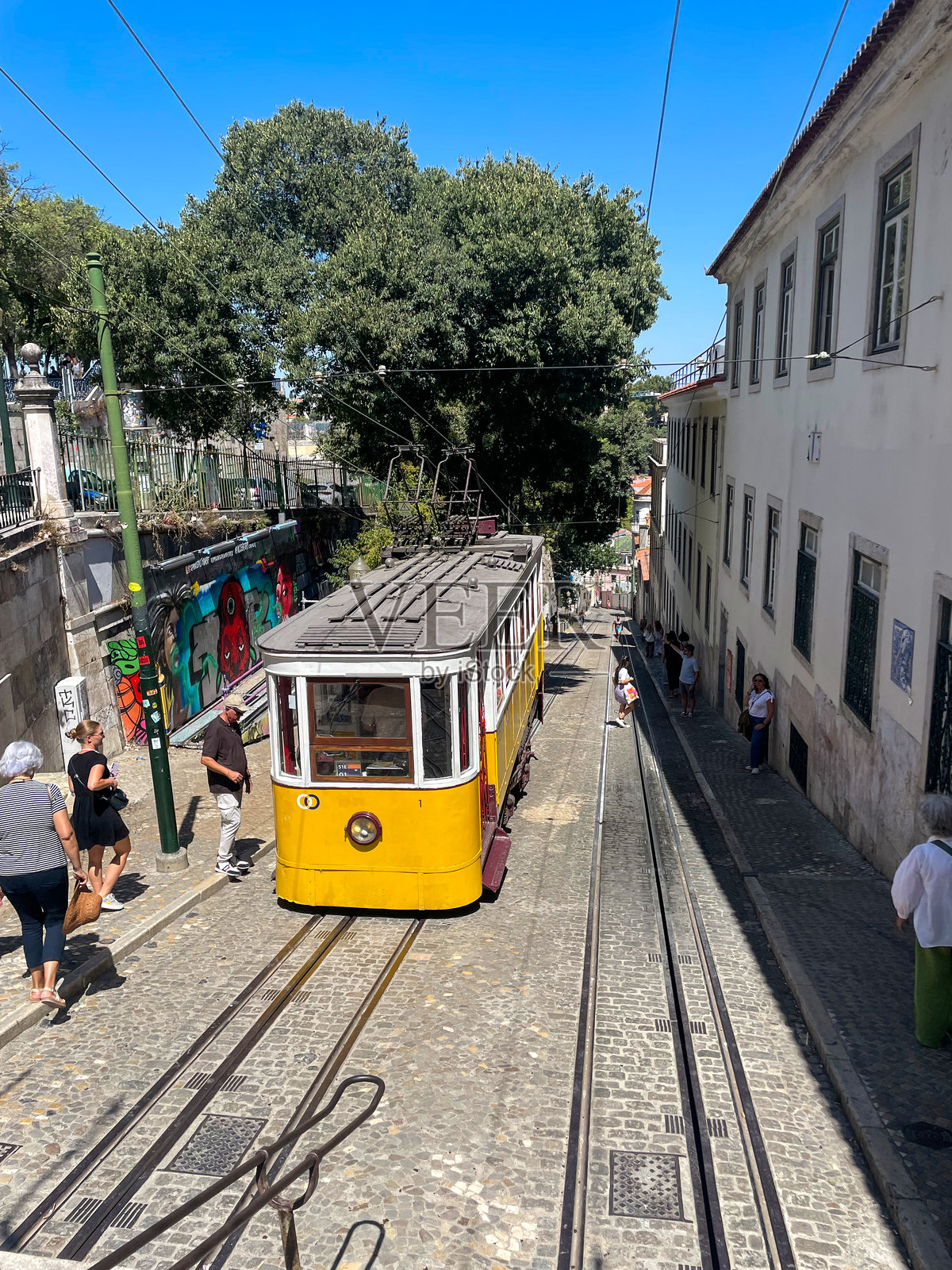 一辆历史悠久的黄色电车在葡萄牙里斯本陡峭的鹅卵石街道上行驶照片摄影图片