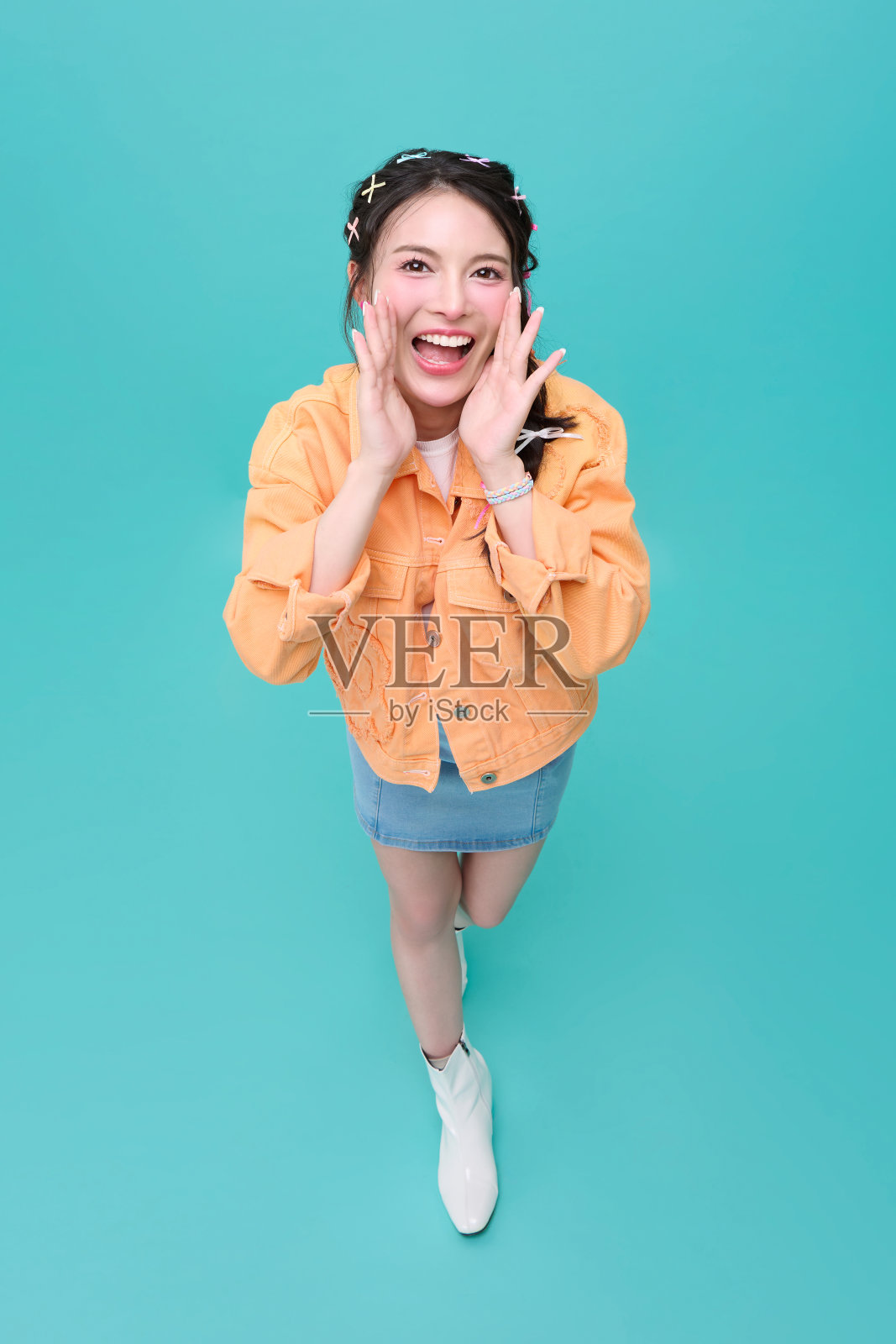 俯视年轻亚洲少女在蓝色背景上大声宣布折扣。演讲和广告宣传概念。照片摄影图片