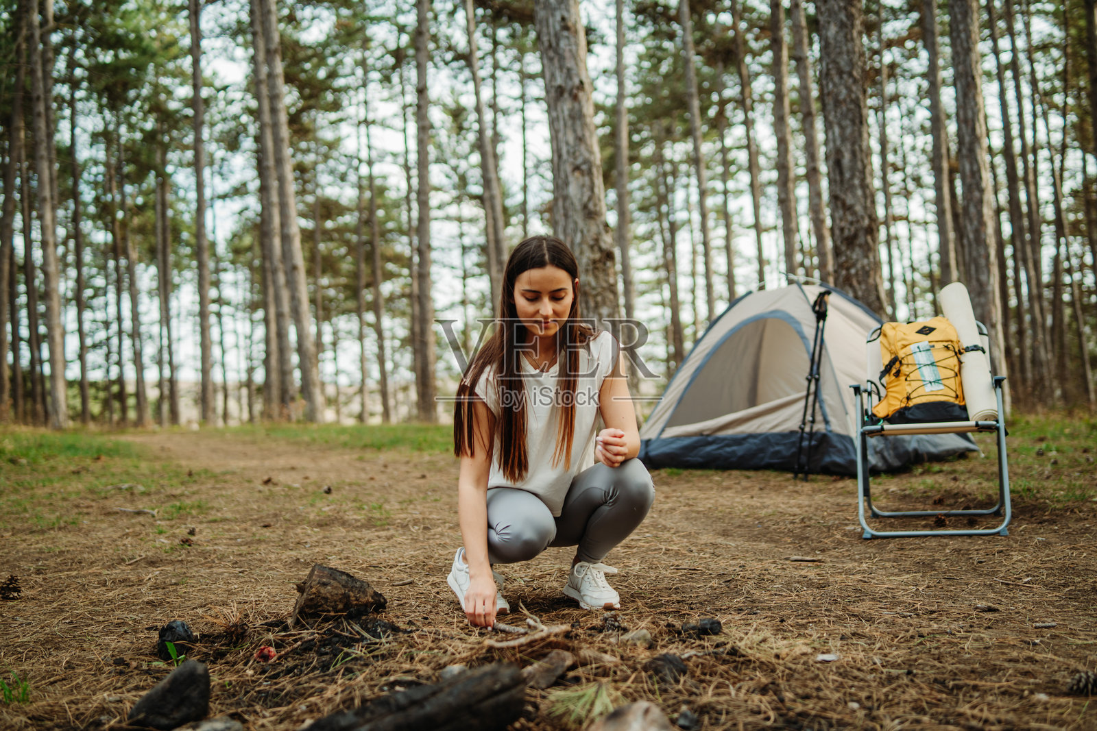 年轻的白人女性在风景如画的森林中为夜晚准备营地和篝火照片摄影图片