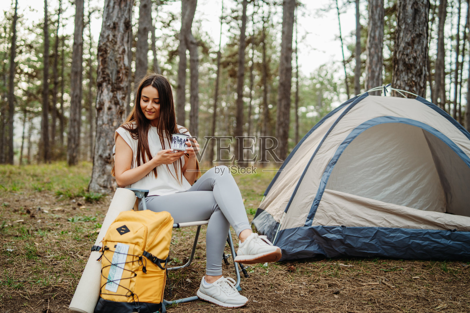 年轻的白人女性在风景如画的森林中为夜晚准备营地和篝火照片摄影图片
