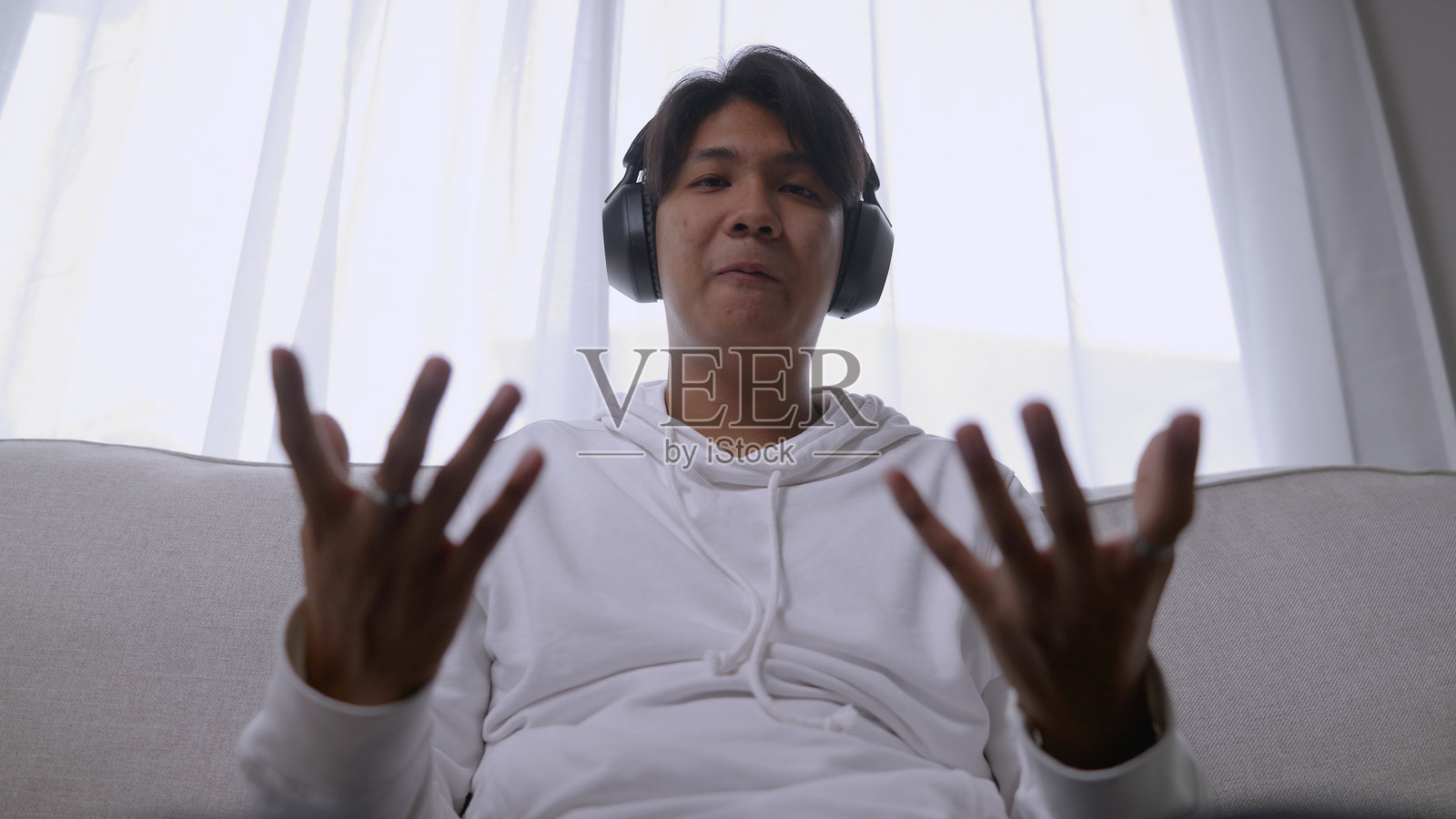 从笔记本电脑的视角 – 亚洲男子在家沙发上工作和视频会议4K。照片摄影图片