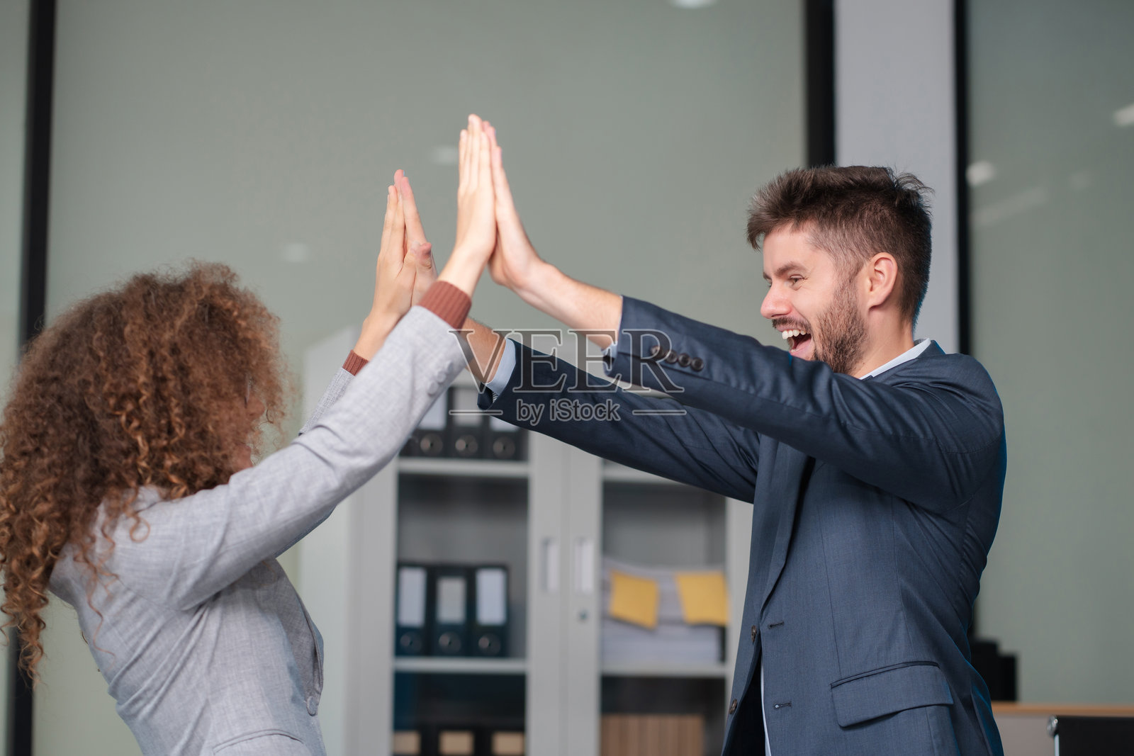 快乐的创意商务人士充满动力，互相击掌庆祝成功的交易。合作会议、伙伴关系、职业发展、团队建设、成功的商业。照片摄影图片