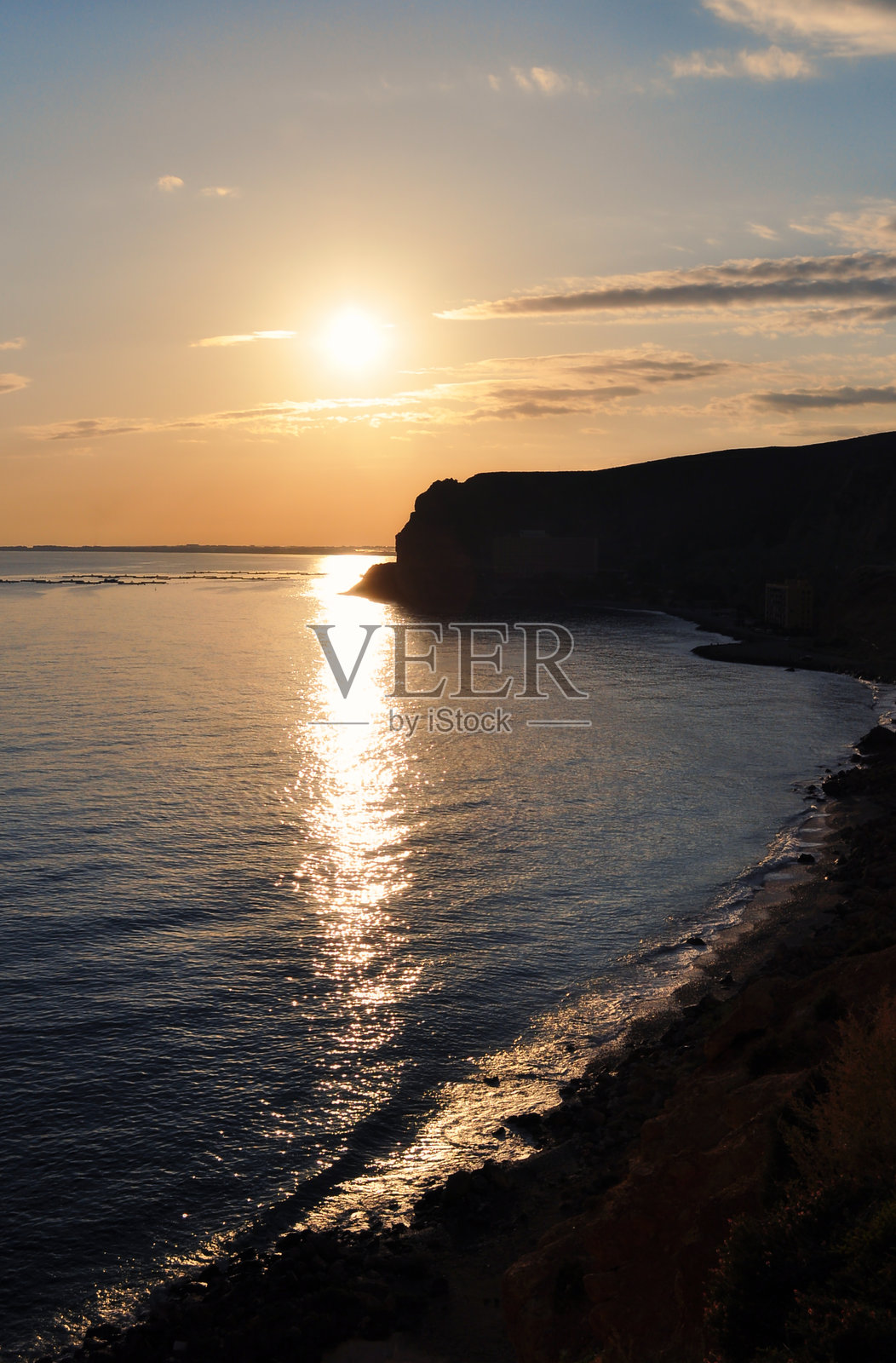 太阳在海面上落下，给水面洒下温暖的光辉。照片摄影图片