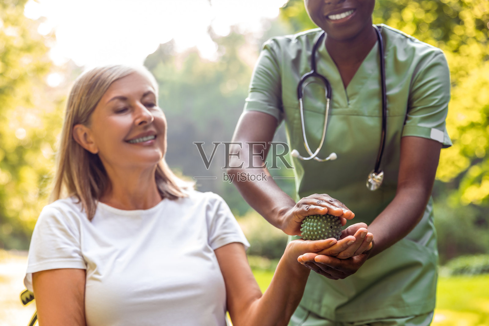 护理人员在绿草如茵的公园里帮助老年人进行康复训练照片摄影图片