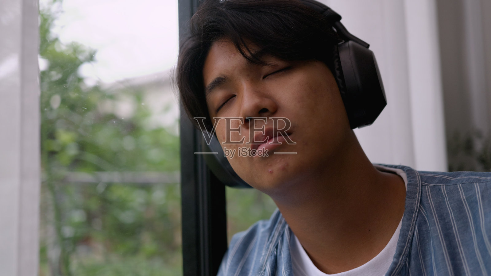 年轻的亚洲男子在舒适安静的空间中休息，享受自然光下的咖啡。4k照片摄影图片