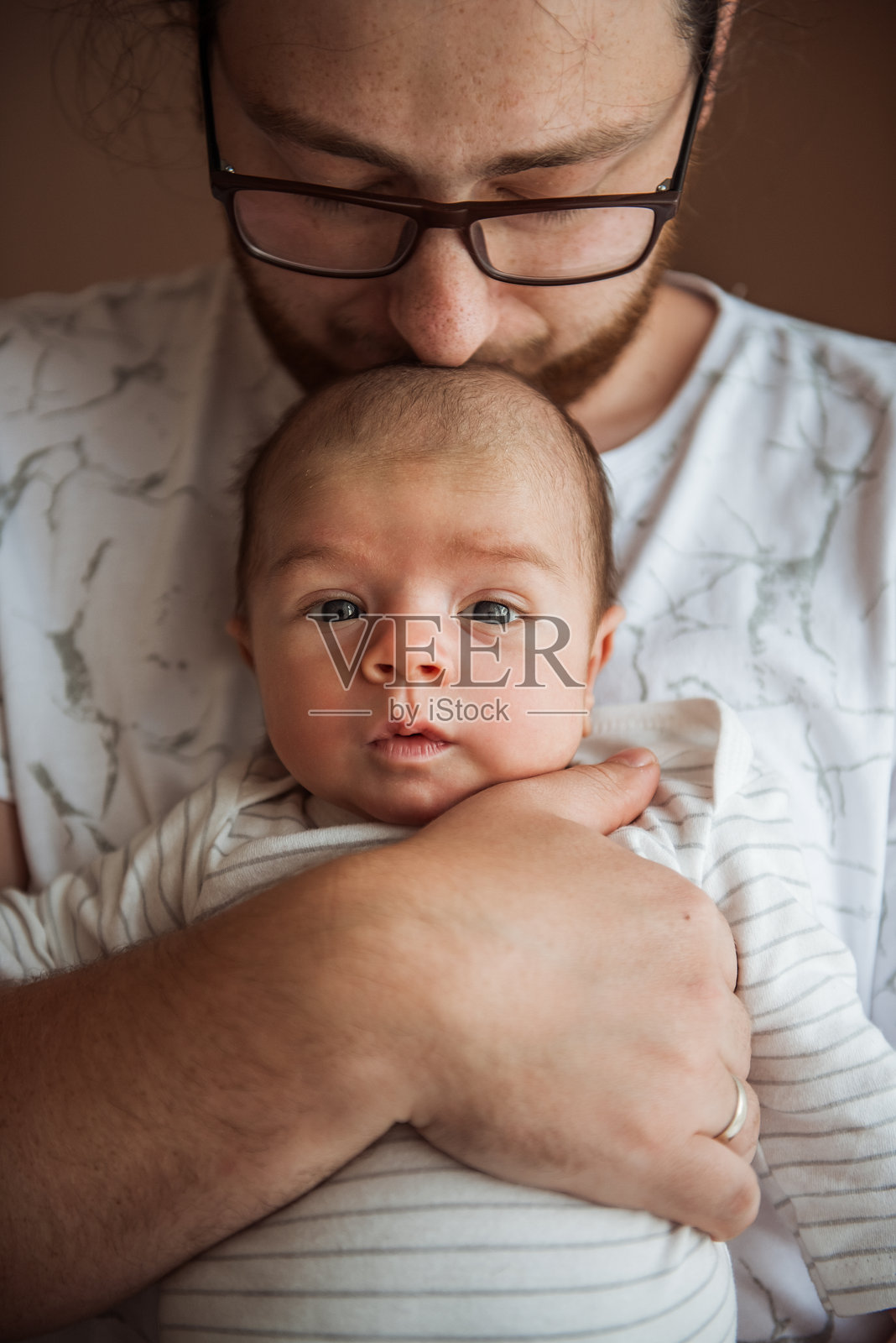 父亲亲吻他的新生儿的头并抱着他照片摄影图片