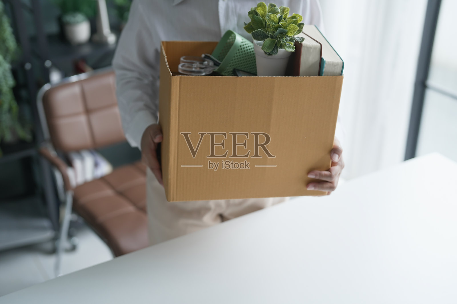 辞职的亚洲女高管正在发送辞职信并打包物品，情绪低落或提着装有文件的纸箱在办公室里，因裁员而退休。照片摄影图片