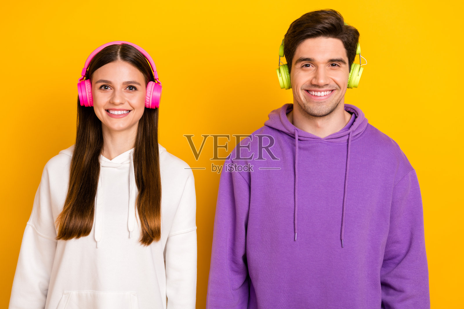 两位快乐积极的人在黄色背景上享受他们最喜欢的单曲照片摄影图片