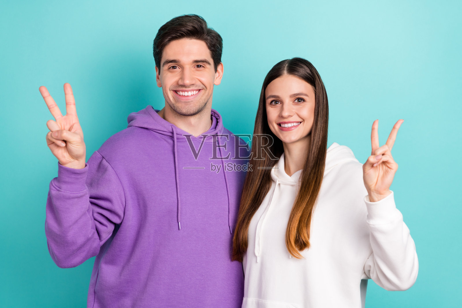 穿着休闲服的快乐学生情侣在蓝色背景前做出“OK”手势的照片照片摄影图片