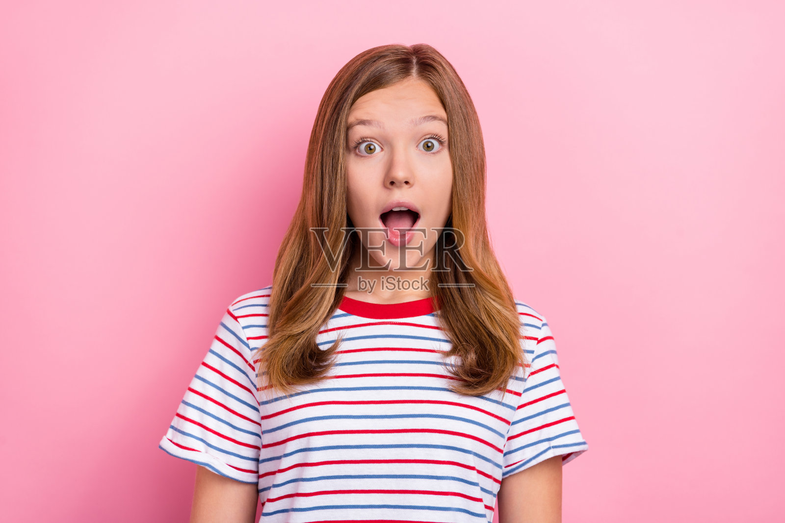 小女孩穿着红色T恤，开心地看着镜头，背景为粉色。照片摄影图片