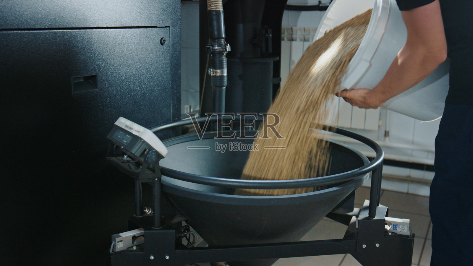 咖啡烘焙过程，工人将生咖啡豆倒入烘焙机料斗照片摄影图片