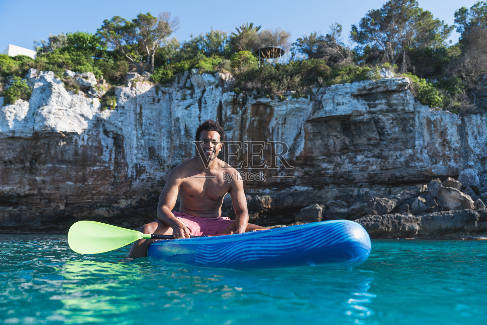 年轻男子在清澈蓝色海洋中放松地划水板照片摄影图片