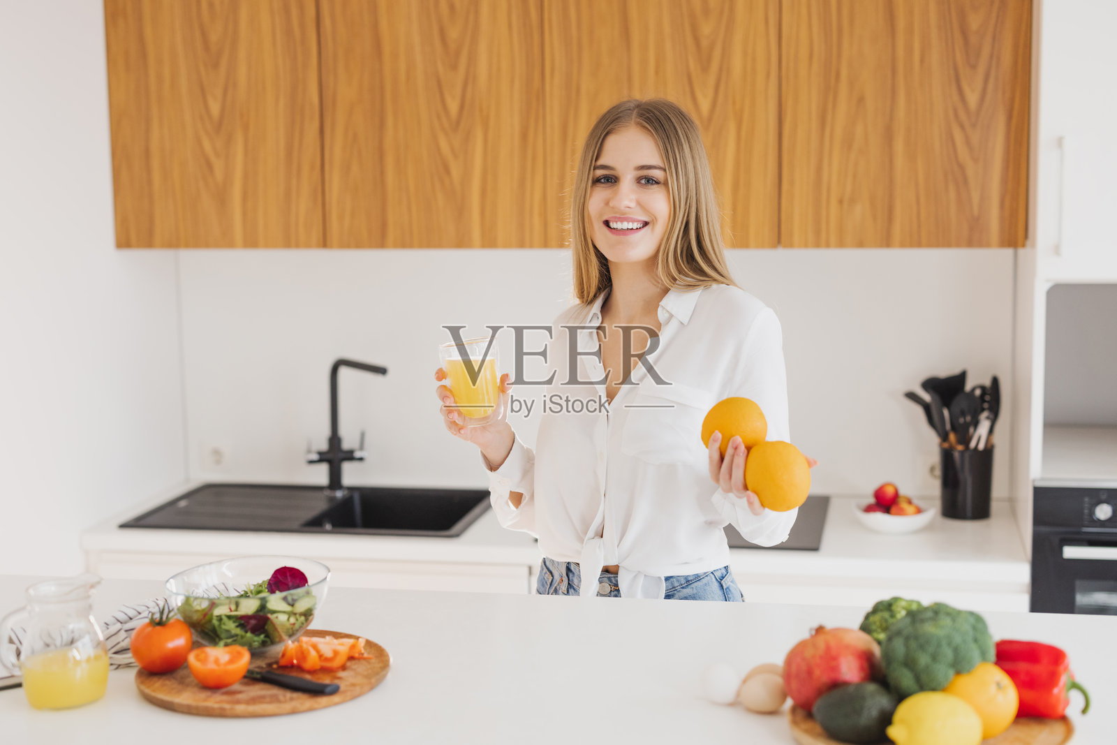 一位快乐的金发女人在厨房里喝果汁照片摄影图片