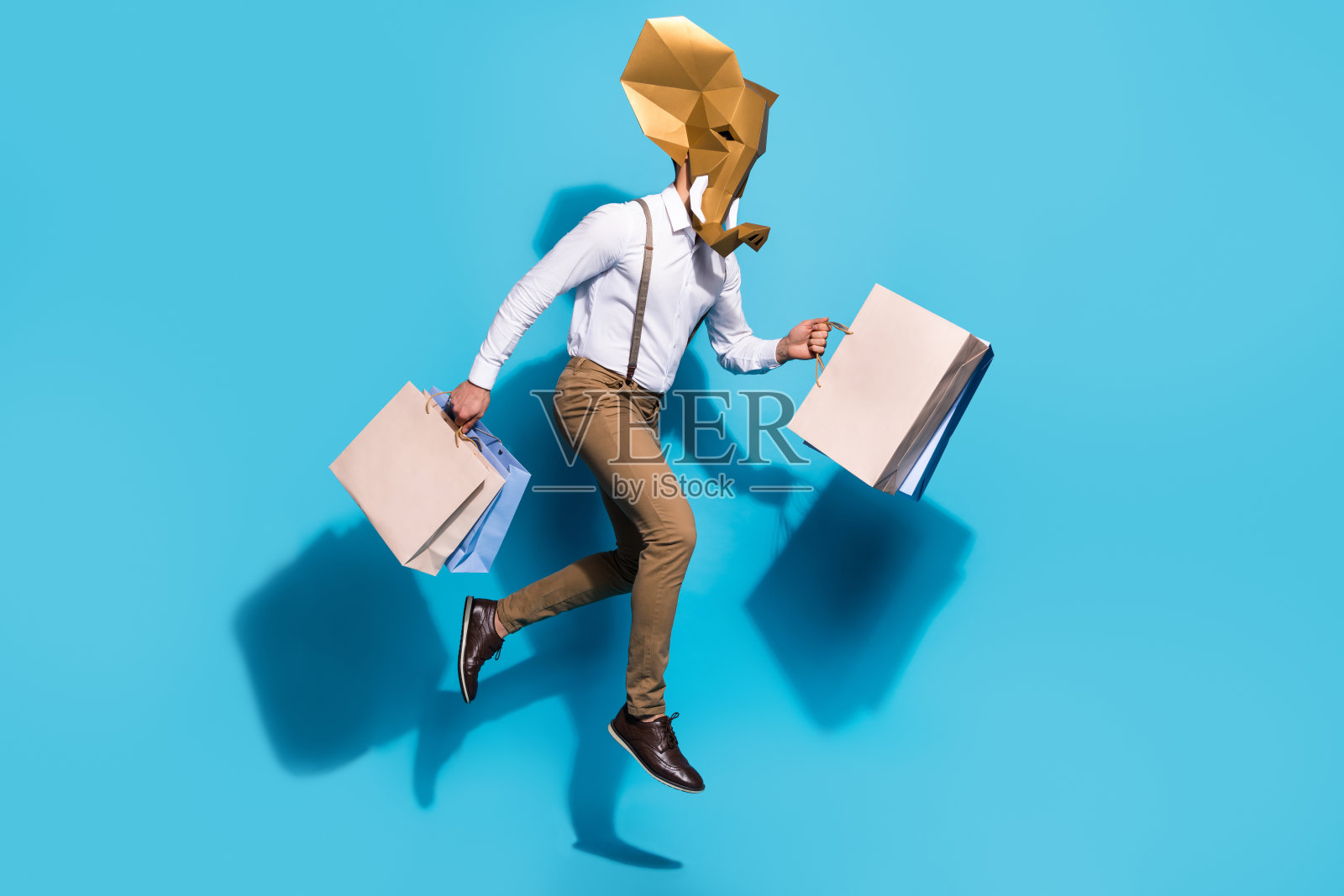 年轻男子全身侧面照，跑步者急匆匆地在商店里挑选礼物，背景为蓝色。照片摄影图片