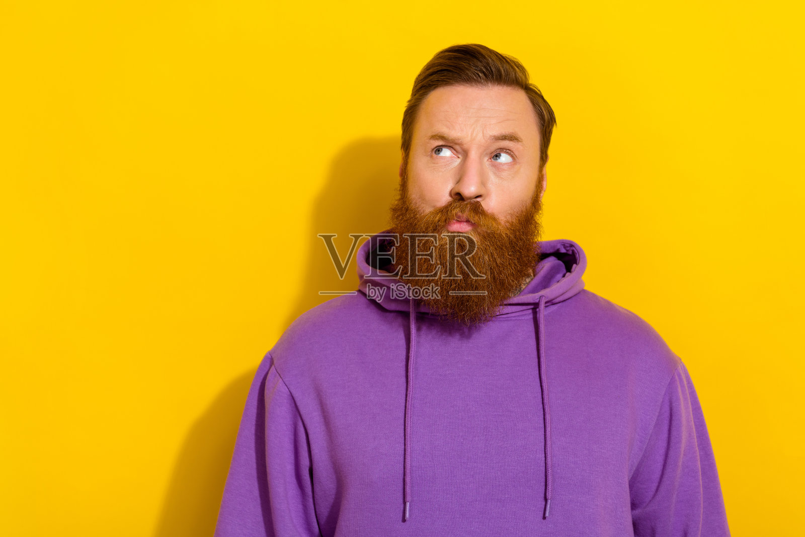 年轻英俊的粗犷男士肖像，目光空洞，独自一人，背景为黄色。照片摄影图片