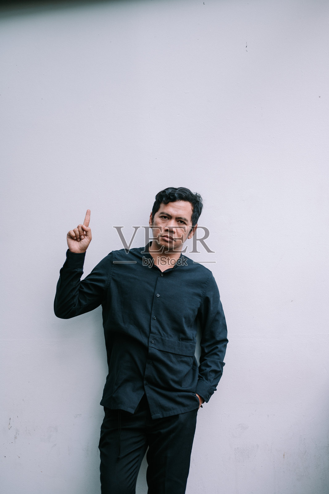 男子指向上方，提供解决方案，背景干净中性。照片摄影图片