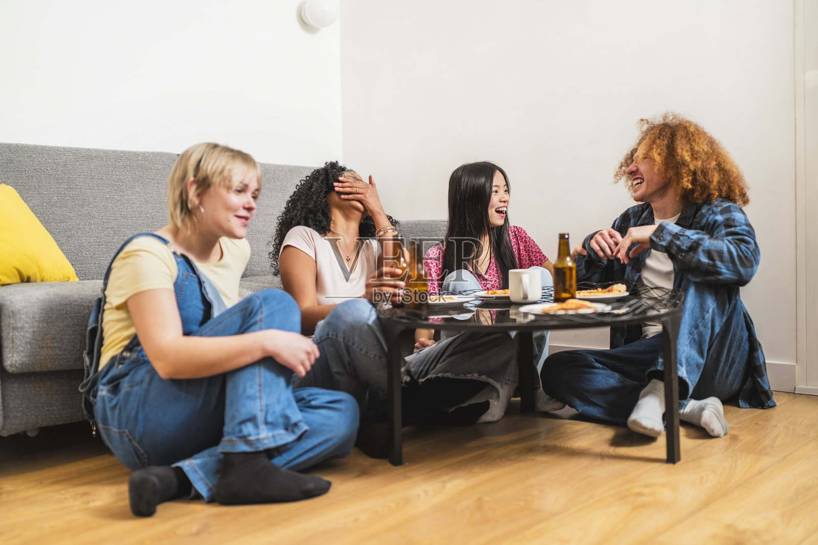 年轻的多民族朋友们在家享受比萨和啤酒照片摄影图片