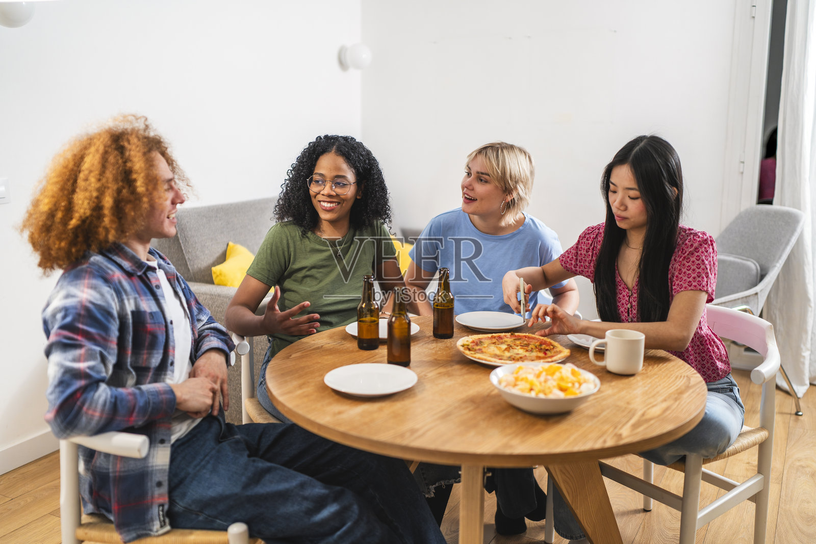 年轻的多民族朋友们在家享受比萨和啤酒照片摄影图片