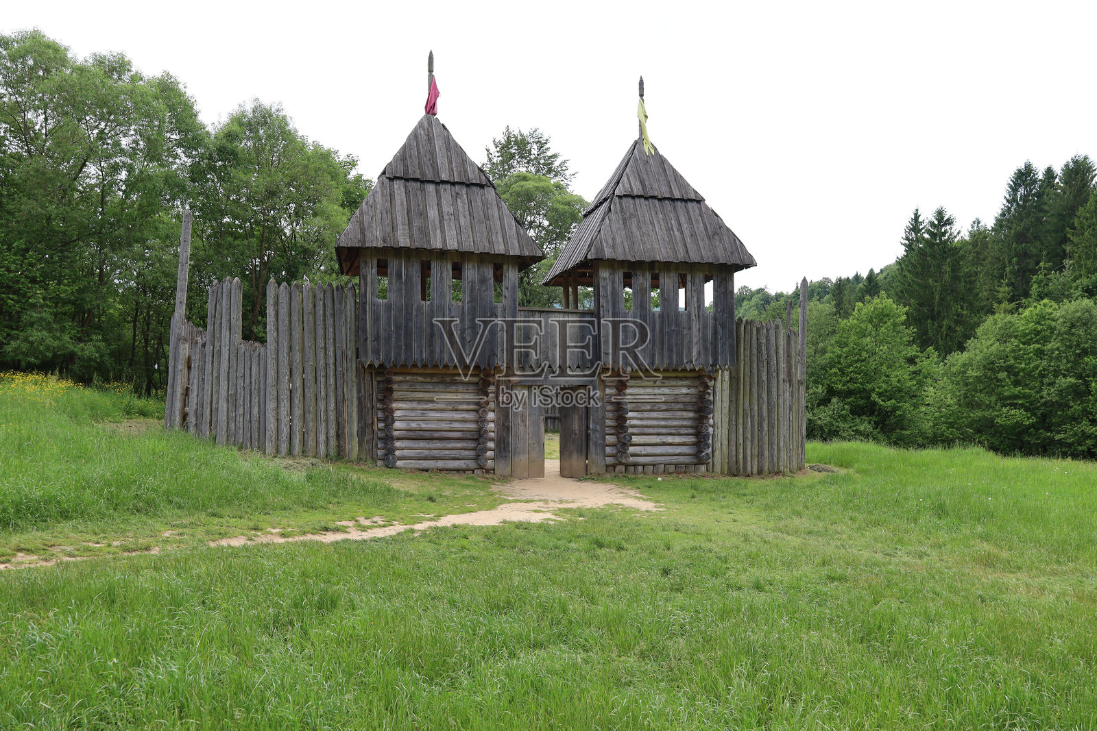 乌里赫，乌克兰 - 2024年6月8日：一座重建的木制堡垒，配有栅栏和瞭望塔，坐落在森林中的绿草地上，营造出古老时代的氛围。照片摄影图片