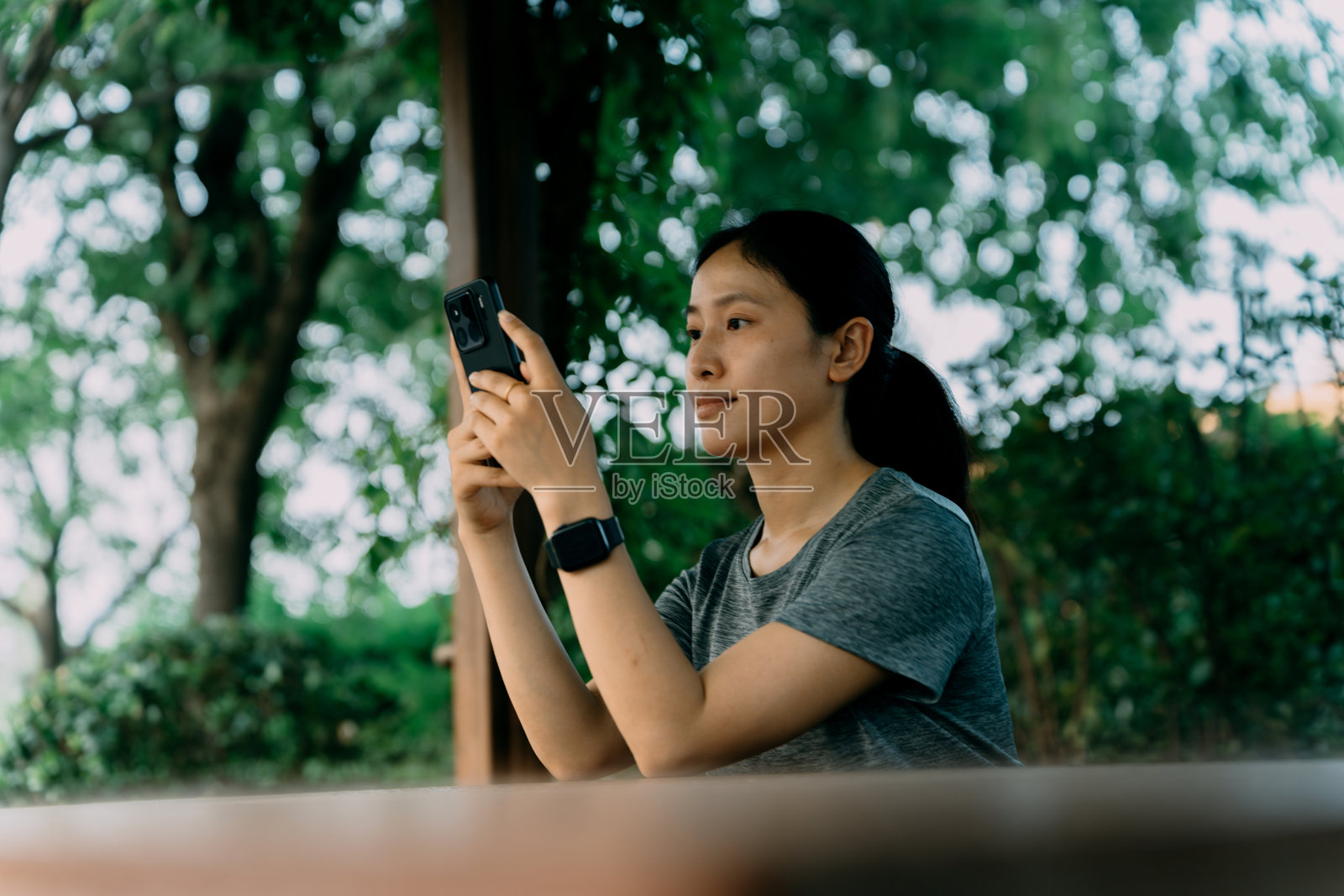 一位穿着运动服的亚洲女性在公园里打电话照片摄影图片
