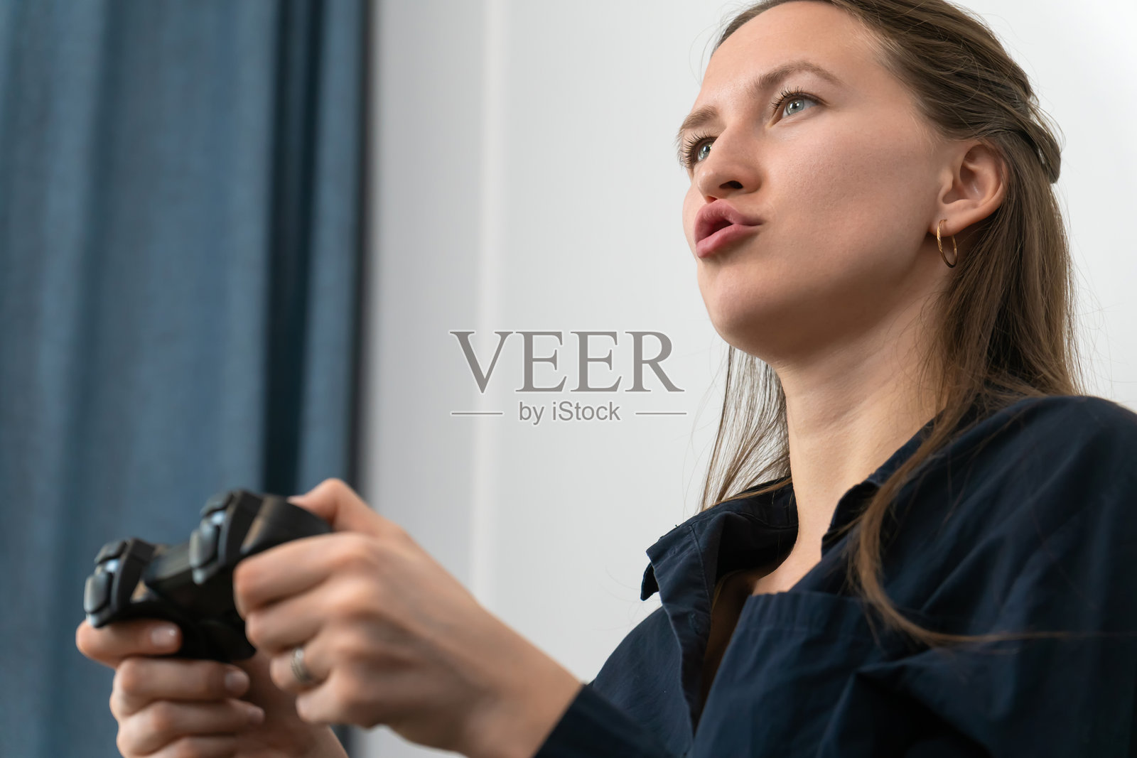 年轻女性专注地握着操纵杆，完全沉浸在玩电子游戏中，享受着在舒适客厅的闲暇时光。照片摄影图片