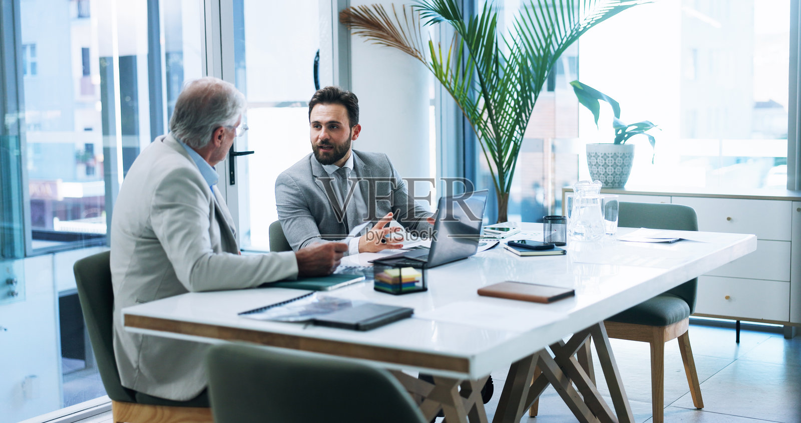 商务人士在办公室使用笔记本电脑进行团队讨论，策划或头脑风暴保险策略，手中拿着纸张。与老板的会议和对话，讨论报告、风险管理和解释想法。照片摄影图片