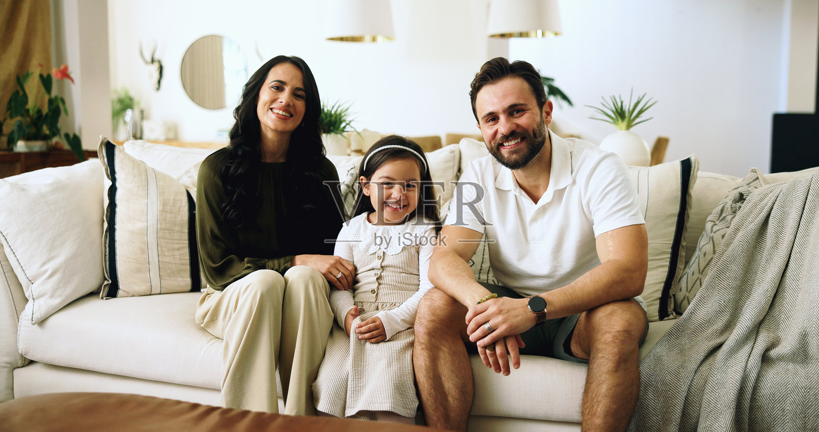 快乐的家庭肖像，父母、孩子和沙发在家中共享爱、亲密和放松。妈妈、爸爸和女孩在公寓的沙发上微笑，男人和女人与女儿在一起。照片摄影图片