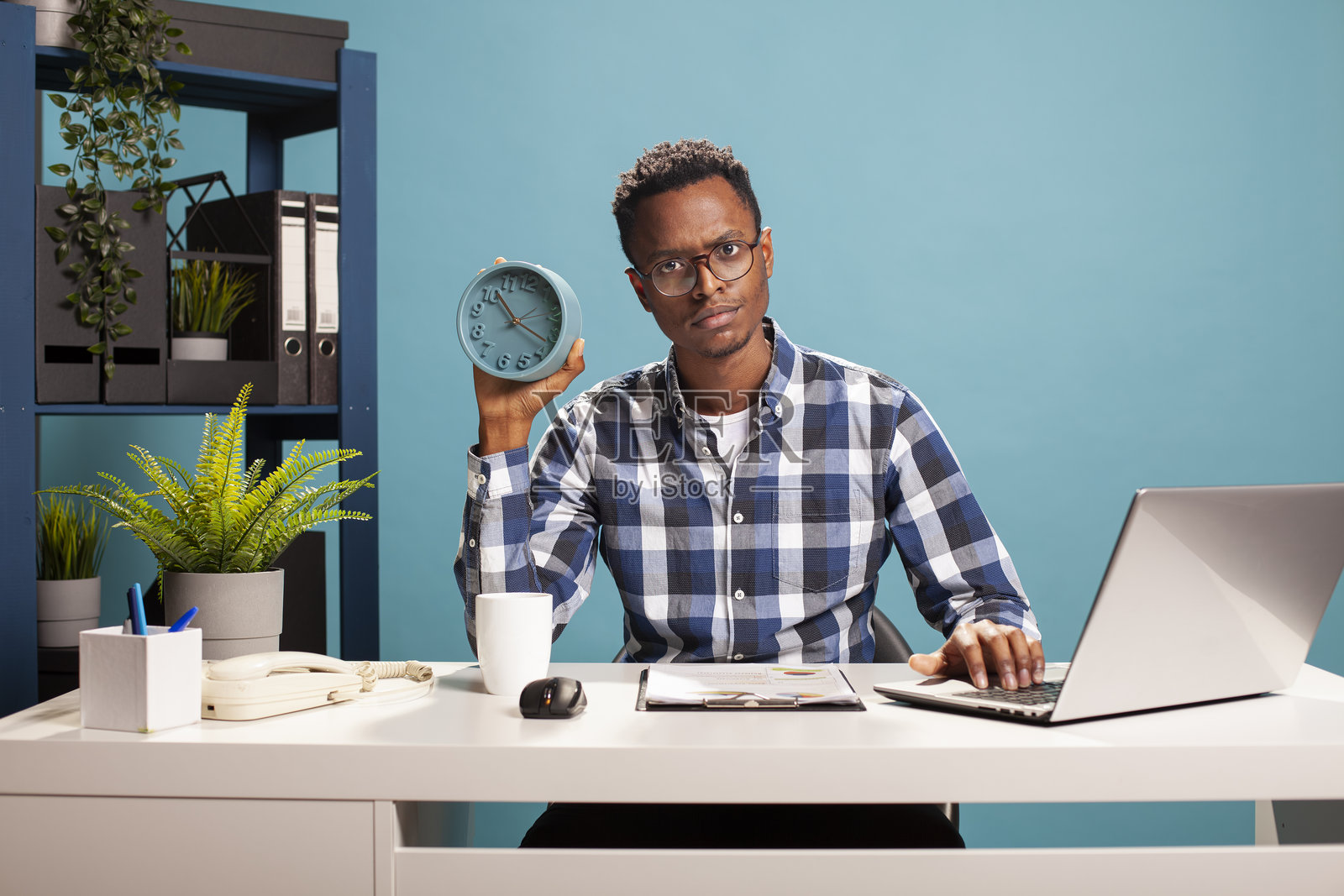 烦恼的经理指着时钟上的时间照片摄影图片