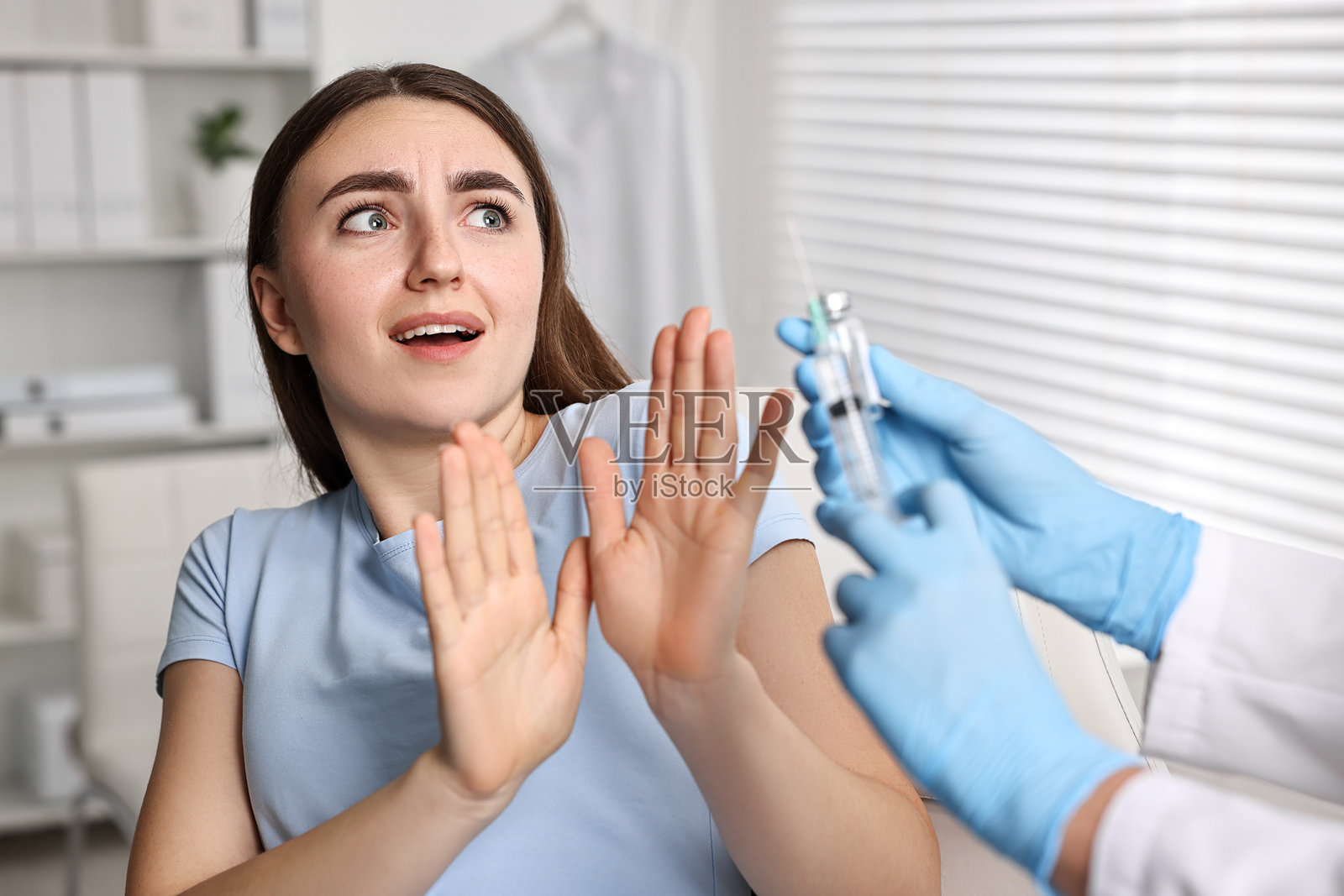 牙科恐惧症。诊所里，拿着注射器和药瓶的牙医在害怕的女性身边，特写镜头。照片摄影图片
