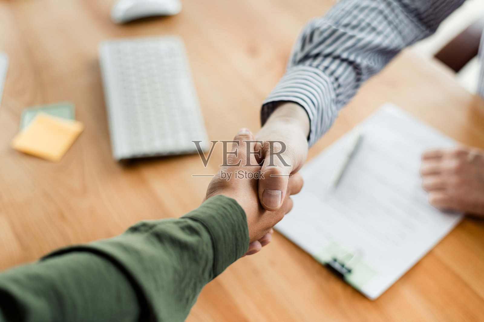 办公室环境中两位同事握手的特写，象征着一致、合作与伙伴关系照片摄影图片