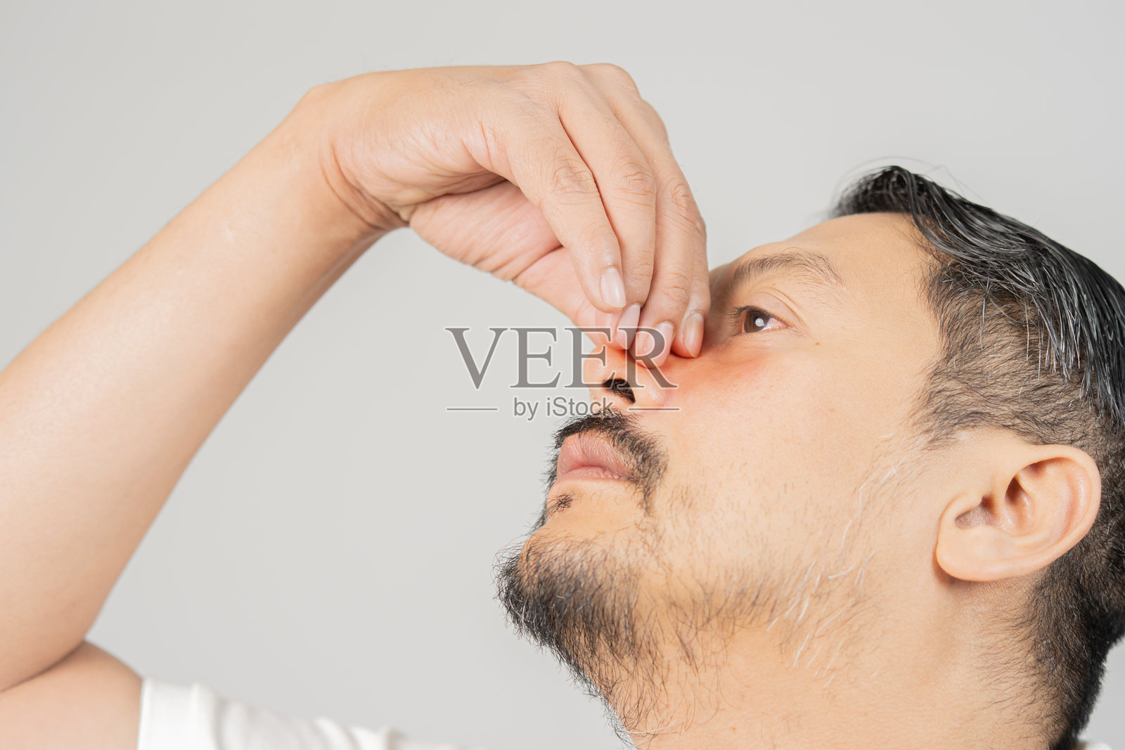 悲伤的男人仰望着，捏着鼻梁。上颌窦疼痛，流鼻涕，鼻中隔。照片摄影图片